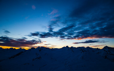 Naklejka na ściany i meble Peaks silhouette in the Swiss alps. Colored sunset in winter.