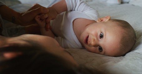 Authentic shot of young happy neo mother is playing with her newborn baby in a nursery in a...