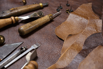 Leather craftman's work desk. Pieces of leather and working tools in the tailoring workshop.