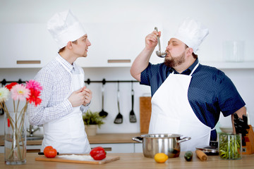 Chef takes an exam with an intern and tastes a soup from a pot