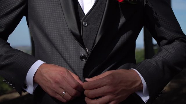 The man fastens his tuxedo.Buttoning a jacket. Stylish man in a suit fastening buttons on his jacket