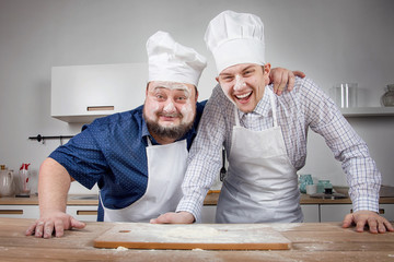 two chefs fool around in the kitchen and throw flour at each other

