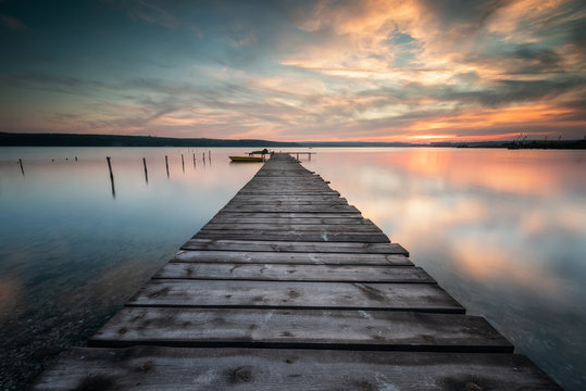 Magnificent long exposure lake sunset with boat and a wooden pier