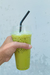 Iced green tea in glass on the wooden table Background glass windows and tree.