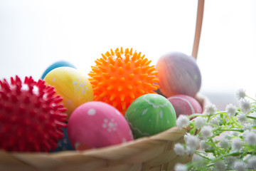 Virus model of Coronavirus disease COVID-19 with colorful easter eggs in basket with flowers on a wooden table background