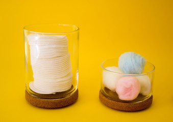 colored cotton wool ball, cotton discs inside glass small container with wooden top. Yellow...