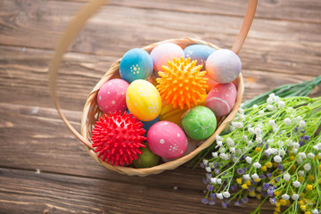 Virus model of Coronavirus disease COVID-19 with colorful easter eggs in basket with flowers on a wooden table background