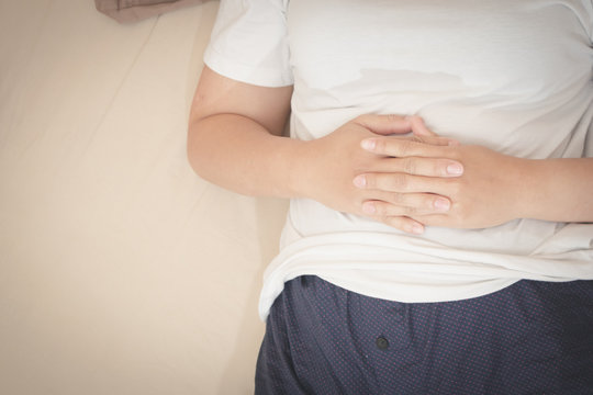 Asian women use their hands to grasp the stomach, showing severe abdominal pain healthcare and medical concept