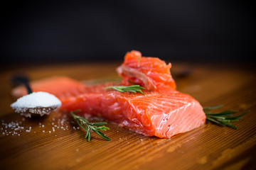 salty red fish on a fork, wooden background