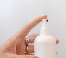 Finger of a woman holding bottle sntibacterial spray for sterilization on white background