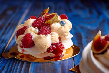Two dessert Pavlova with raspberries on old blue wooden table. Meringues on a rustic background