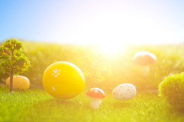 Decorated easter eggs in green grass on sunset sky background.