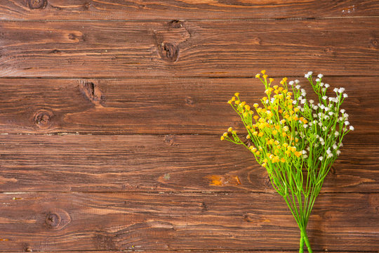 Colorful yellow, white and lilac spring flowers on rustic brown painted wooden planks. View from above.
