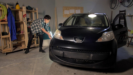 A guy inspects a car wheel in a garage