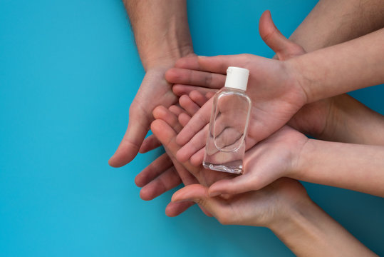 Family holding antiseptic gel in hands on blue background. Flu, illness, pandemic or individual protect on quarantine concept. Top view - Powered by Adobe