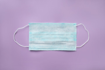Prevent coronavirus. Surgical mask with rubber ear straps. Simple white air protection mask on the color background. 