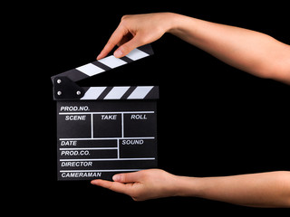 Human hand holding film clapper board isolated on black background with clipping path