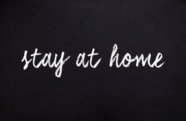 Fototapeta premium Illustration with message to stay home on a blackboard written in chalk