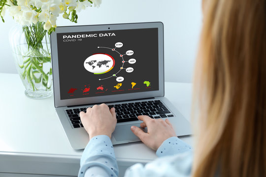 Woman with laptop checking pandemic data indoors, closeup. Coronavirus outbreak
