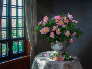 Still life with a bouquet of blooming pink rose hips