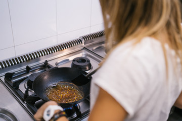 Young woman chef preparing noodles with chopsticks in a wok a kitchen in a modern restaurant