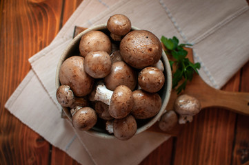 Close-up of brown mushrooms in a bowl, on wooden table, top view