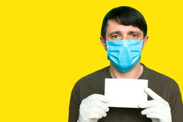 Portrait of an man in a medical mask and gloves. He is holding a clear piece of paper. Coronavirus with blankspace. Coronavirus concept of danger for the people