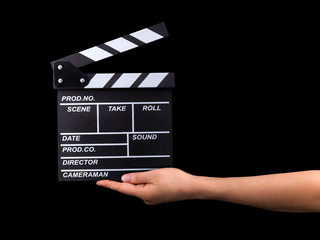 Human hand holding film clapper board isolated on black background.