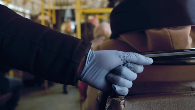 A man rides in a public transport and holds a handrail in his protective medical squirt. Coronavirus infection and epidemic protection concept, pandemic