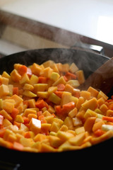 Chopped carrots and butternut squash in a wok. Selective fcous.