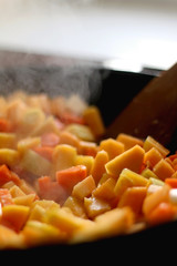 Chopped carrots and butternut squash in a wok. Selective fcous.