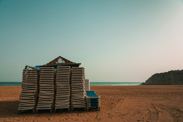 Pile of sunbeds, ready for season on Algarve coast, empty beach in Albufeira. Tourism and travel...