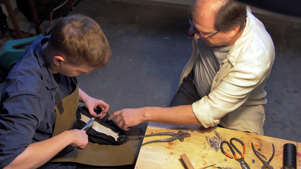 Master teaches man in a shoe workshop