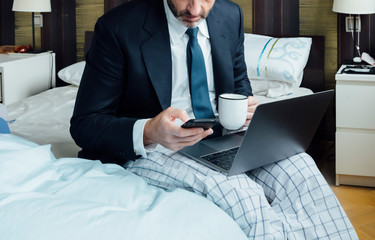Businessman fresh out of bed with laptop and smart phone