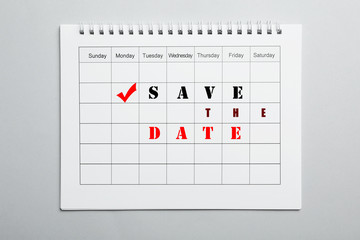 Blank calendar with phrase SAVE THE DATE on light grey background, top view