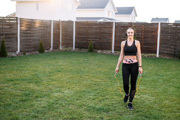 Young woman jumps with a skipping rope outdoors