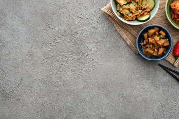top view of bowls with tasty kimchi hear chopsticks on concrete surface