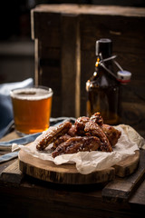 Chicken wings with sesame seeds and glass of beer with bottle on wooden background