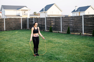 Young woman jumps with a skipping rope outdoors