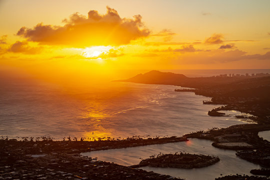 A sunset over the Hawaiian Island of Oahu as seen from a mountain top with the city of Hawaii Kia in the foreground and Diamond Head in the distance.  Image captured from the summit of Koko Head Crate