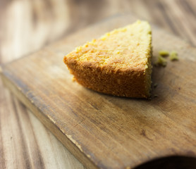 Slice of homemade buttermilk cornbread on a wooden cutting board. 