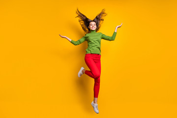Fototapeta na wymiar Full body photo of funky pretty lady jumping high throwing hairdo air feel freedom in veins wear casual green jumper red pants isolated yellow color background