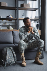 sad african american soldier in military uniform suffering from PTSD at home