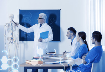 Medical students and professor studying human skeleton anatomy in classroom