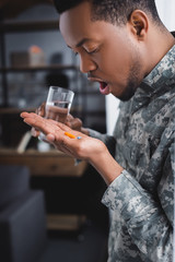african american soldier taking pills and suffering from PTSD at home