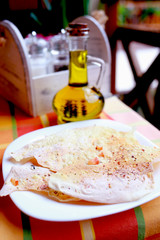 Appetizing hot pita bread on a white plate served with olive oil in a cafe, close-up. Healthy eating concept