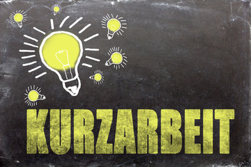 Kurzarbeit Text auf Kreidetafel mit Glühbirnen