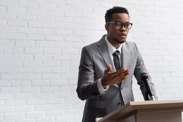 confident african american business speaker on tribune with microphone in conference hall