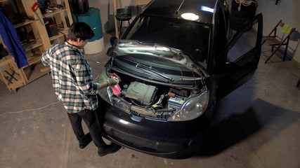 Fototapeta na wymiar Man is repairing car engine in the garage