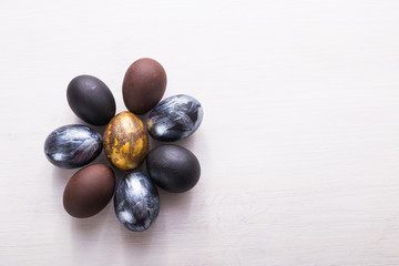 Holidays, traditions and Easter concept - Dark stylish easter eggs on white wooden background with copyspace.